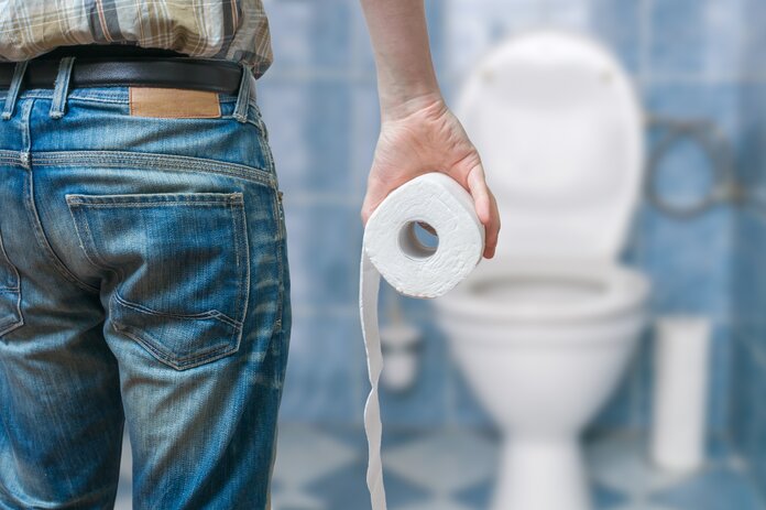 Toilettengang, © vchal, Shutterstock Mann von hinten geht mit einer Rolle Klopapier zur Toilette.