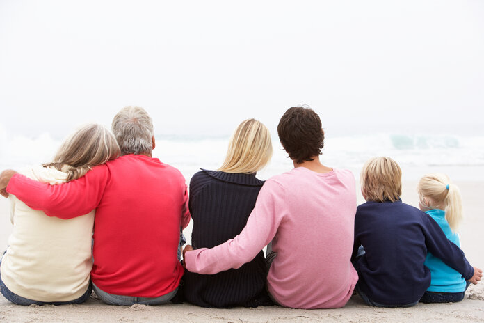 Familie am Strand, © Monkey Business Images, Shutterstock Familie aus drei Generationen sitzt am Strand